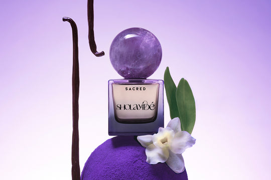 SACRED Eau de Parfum by SHOLAYIDÉ positioned on top of a purple sculpture.