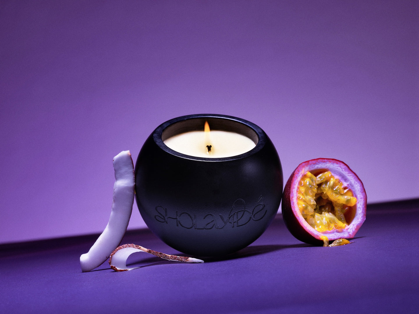 EXALTED vegan scented candle by SHOLAYIDÉ paired with fresh coconut slices and passionfruit.