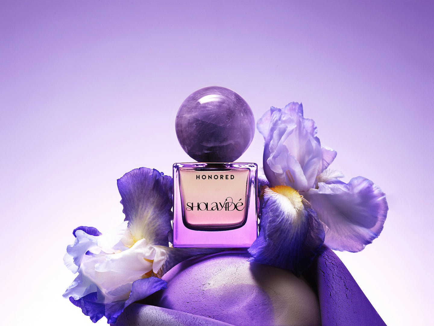 HONORED eco-luxe eau de parfum by SHOLAYIDÉ paired with violet Iris flowers and an amethyst crystal.