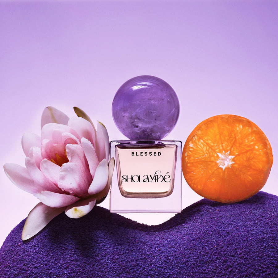 BLESSED by SHOLAYIDÉ, eco-luxe eau de parfum purple ombre bottle with amethyst crystal cap on white background.