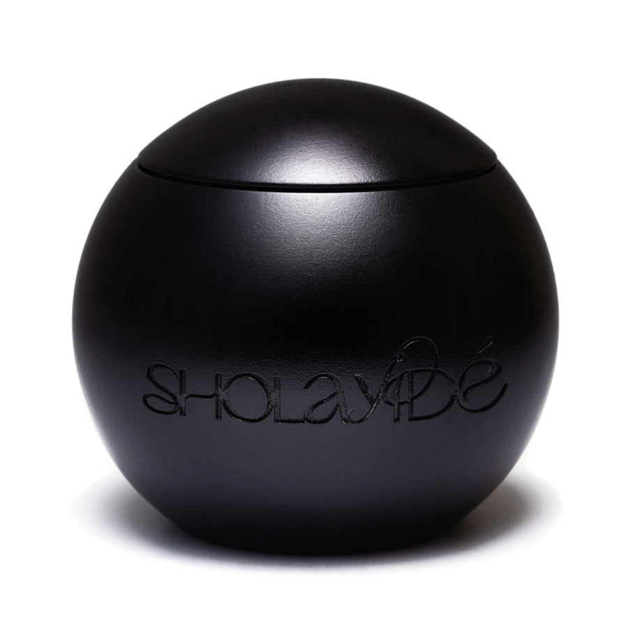 EXALTED by SHOLAYIDÉ, an eco-luxe vegan candle in a black sphere cement candle jar on a white background.