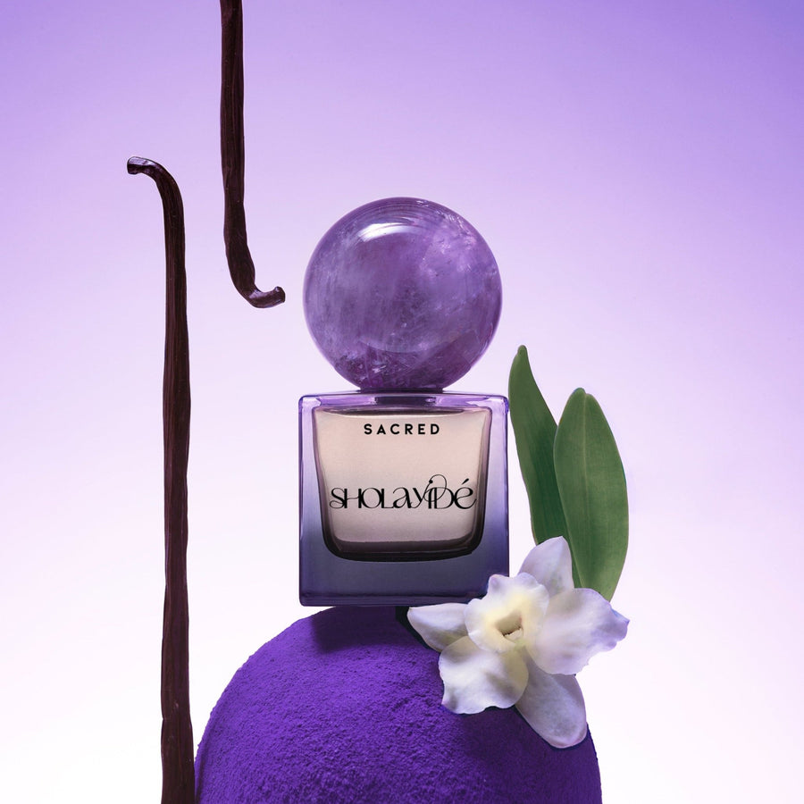 SACRED by SHOLAYIDÉ, eco-luxe eau de parfum purple ombre bottle with amethyst crystal cap on white background.