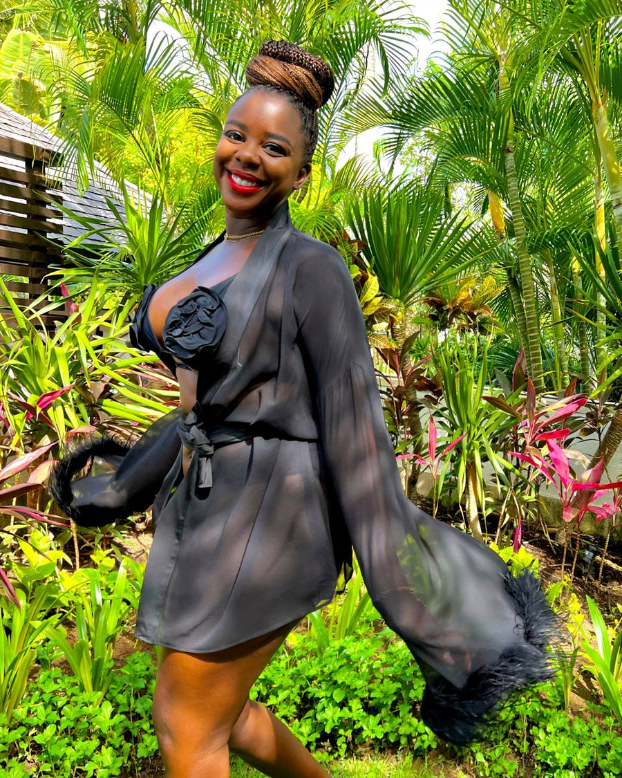 Sholayide Otugalu smiling and posing in a Bali garden wearing the EDEN feather trim robe by SHOLAYIDÉ