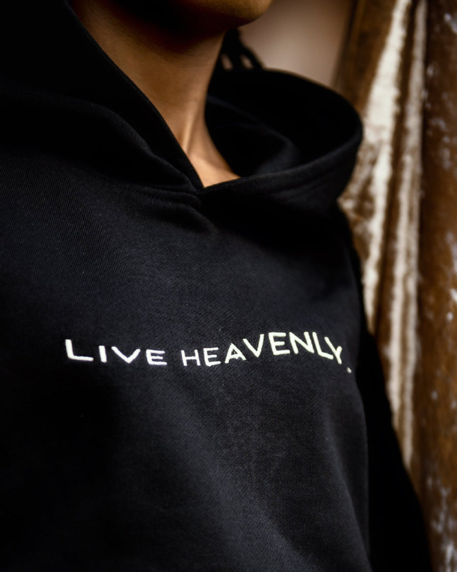 Close up shot of black female model wearing cropped hoodie with white LIVE HEAVENLY embroidery by SHOLAYIDÉ.