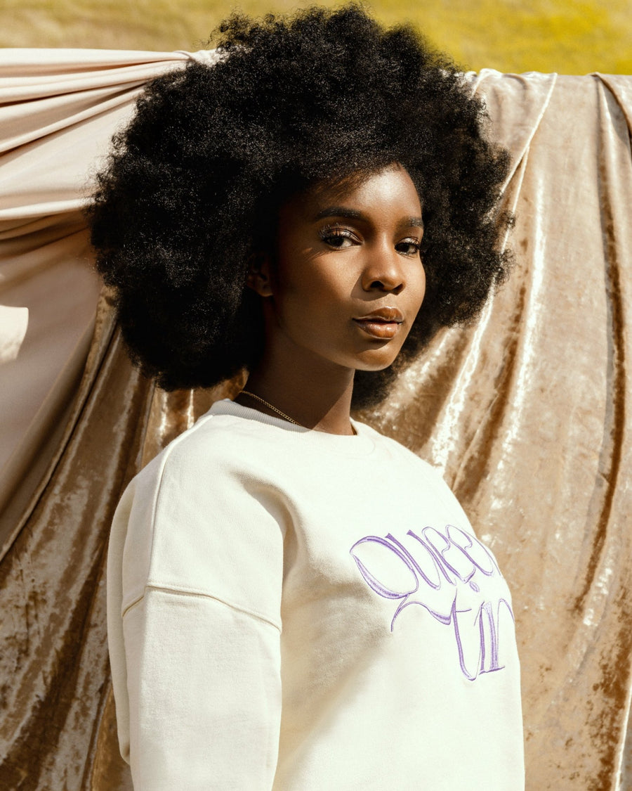 Beautiful black female model with afro hair wearing the cream Queen Ting embroidery sweatshirt by SHOLAYIDÉ.